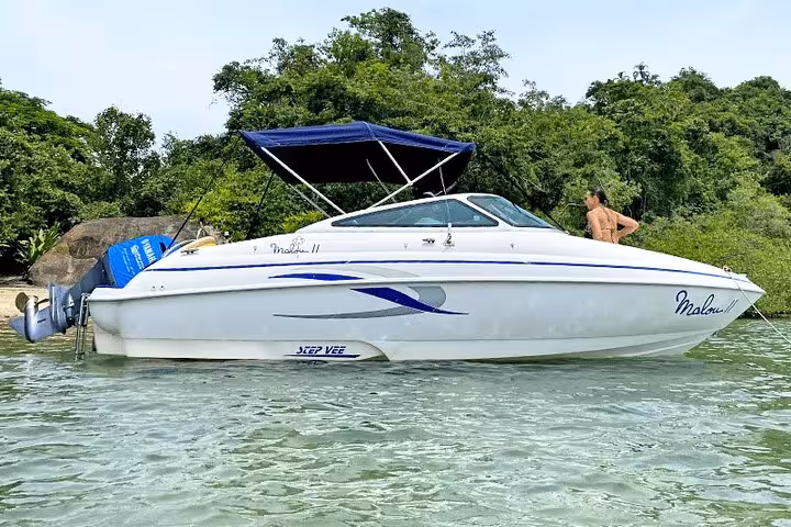 Sleek white motorboat by lush greenery, perfect for Paraty's exclusive boat tours and serene coastal exploration.