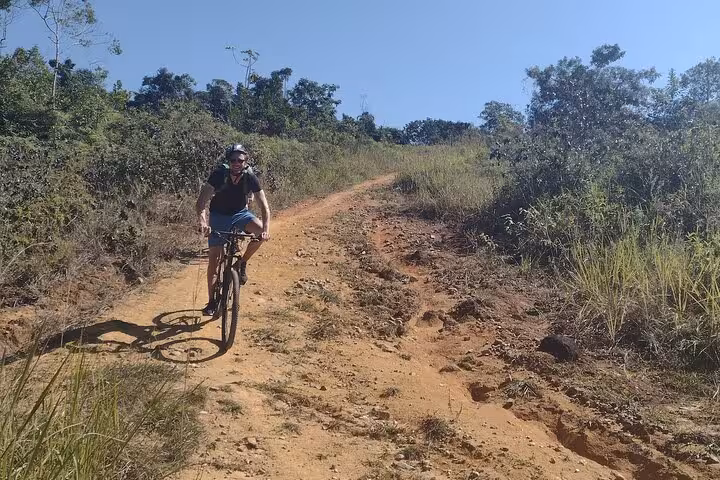 Cyclist navigating a rugged trail surrounded by lush greenery during a guided bike tour in Paraty.