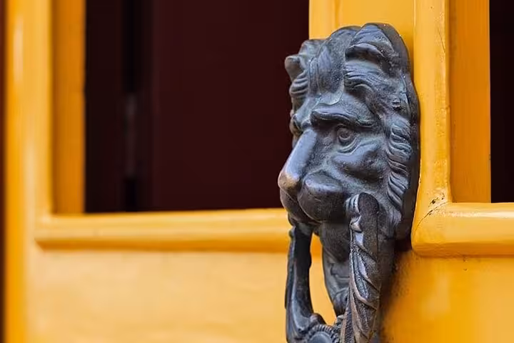 Close-up of a decorative lion-shaped door knocker on a vibrant yellow door in Paraty's historical center.