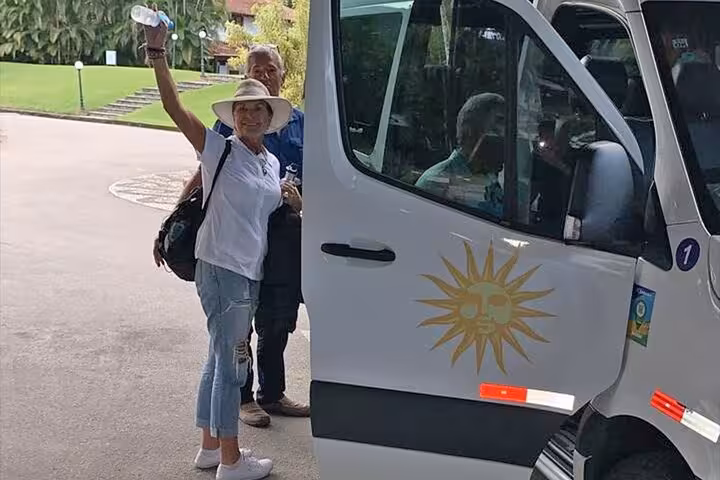 Happy travelers boarding a sun-marked van for a shared transfer from Paraty to Ilha Grande.