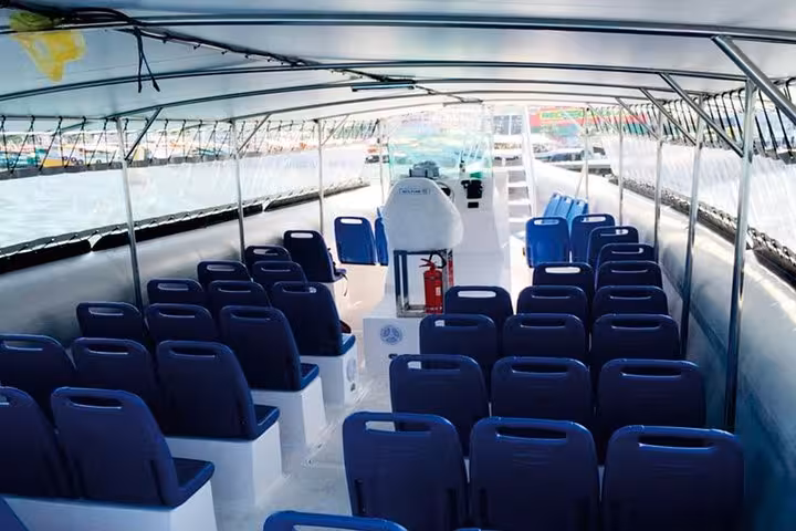 Spacious interior of a transfer boat from Paraty to Ilha Grande with multiple rows of blue seating.