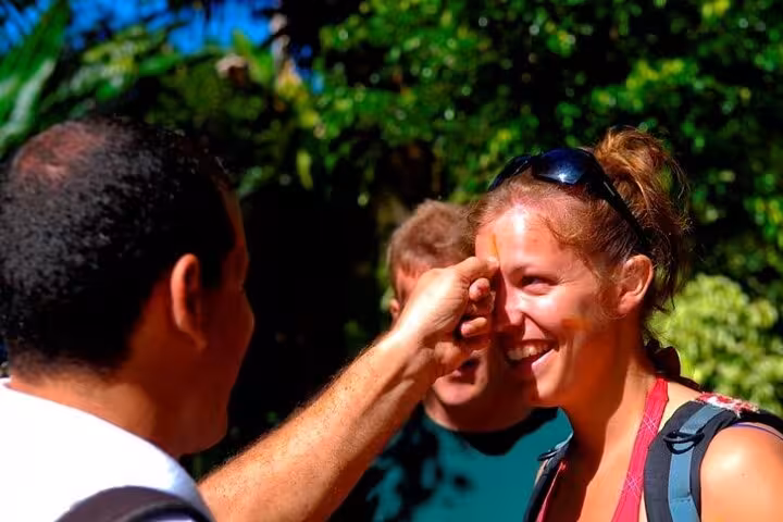 Smiling tourist receiving a local forehead mark during a cultural stop on a Paraty jeep tour.