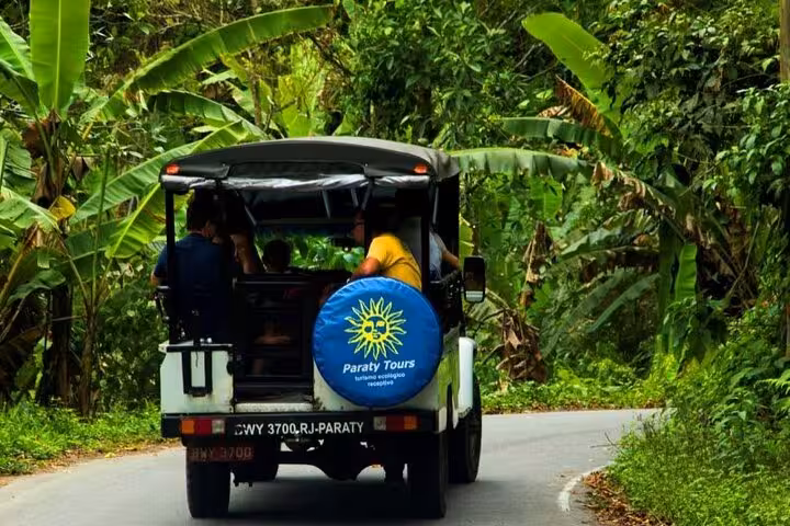 Experience the thrill of a Paraty Tours jeep journey through tropical greenery, showcasing unique rainforest vibes.