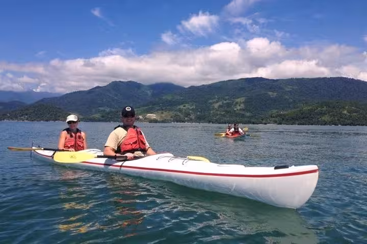 Participants enjoy kayaking on serene waters with scenic mountain views on the Paraty Tours Mangrove and Beach Kayak Tour.