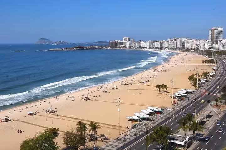 Aerial view of Copacabana Beach in Rio de Janeiro, showcasing the sandy shore, ocean waves, and city skyline.
