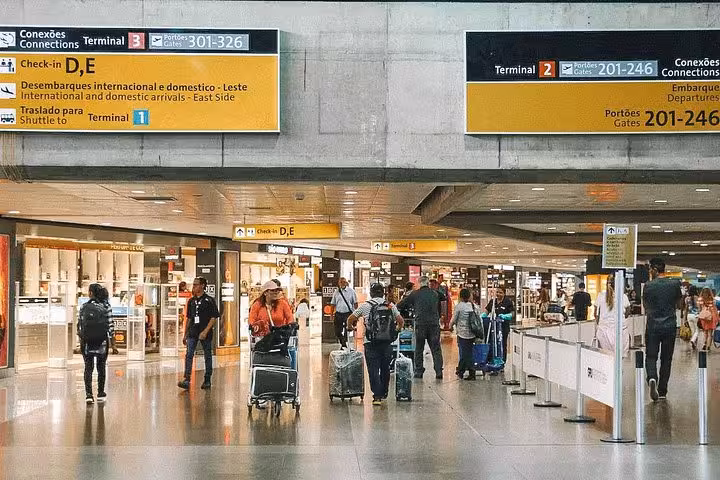 Travelers with luggage at São Paulo airport terminal, indicating arrival point for Paraty to São Paulo shuttle service.