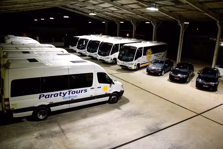 Fleet of Paraty Tours vehicles, including shuttle buses and vans, stationed in a spacious garage for São Paulo transfers.