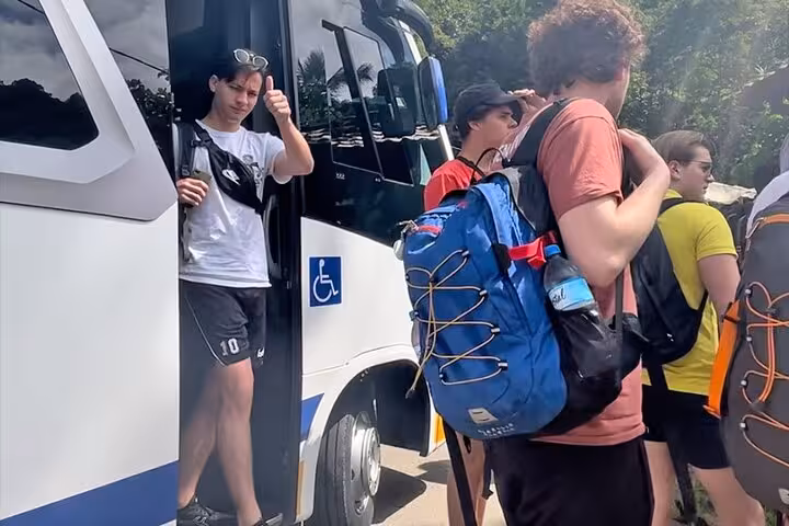 Group of travelers with backpacks exiting a shared transfer bus from Paraty to hotels in Rio de Janeiro, expressing satisfaction.
