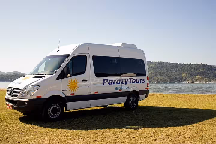Paraty Tours van parked by the scenic waterfront, offering comfortable shared transfers to Rio de Janeiro hotels.