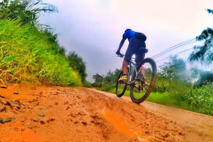 Cyclist on a dirt path surrounded by lush greenery during a bike tour with Paraty Tours, ideal for adventure seekers.
