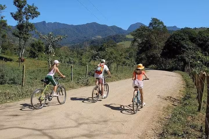 Group of cyclists enjoying a scenic ride through mountains and greenery with Paraty Tours bike rental.