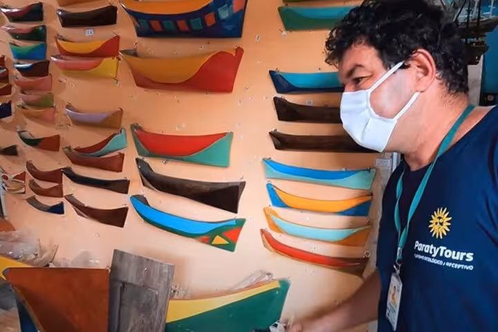 A guide from Paraty Tours explains colorful boat models, showcasing local craftsmanship and culture on the tour.