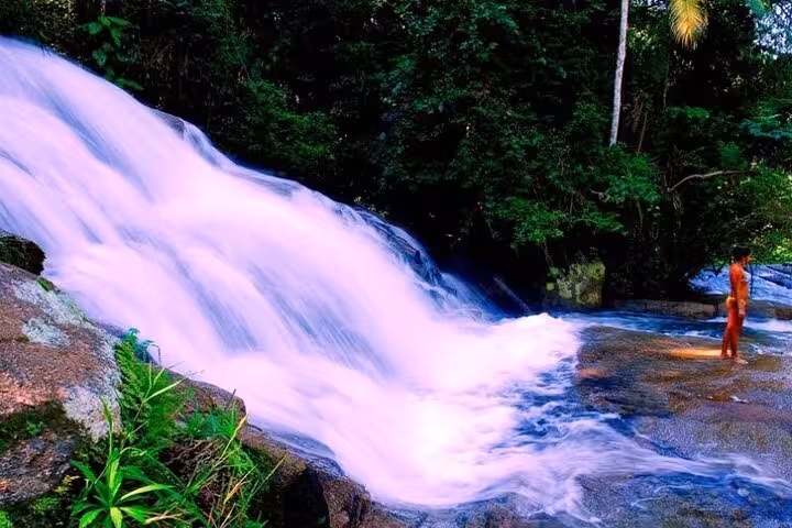 A serene waterfall in Paraty offers a refreshing escape, surrounded by lush greenery and natural beauty.