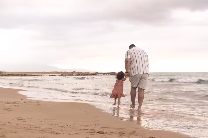 Parent and child walking hand in hand along Gouves beach, creating cherished memories during a private photoshoot.