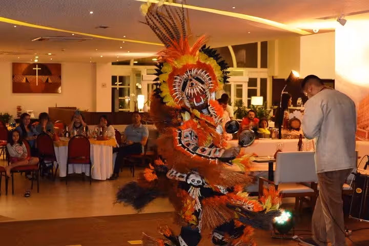 Traditional folklore dancer in vibrant feather costume performing during themed dinner show with live music