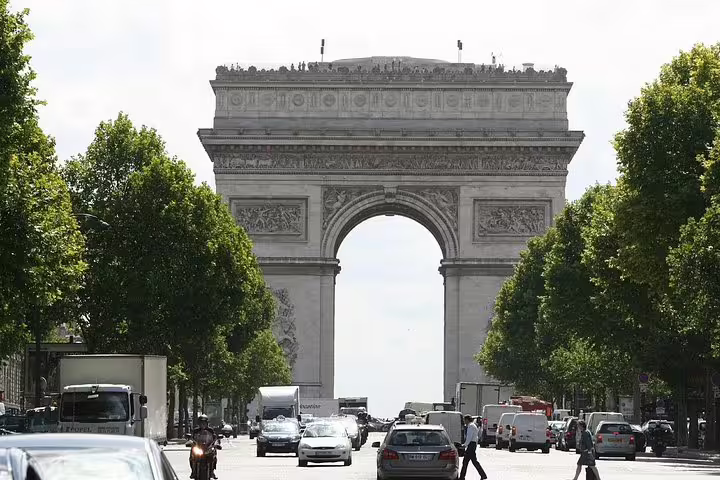 View of the iconic Arc de Triomphe surrounded by bustling traffic, ideal for a Paris layover tour from the airport.