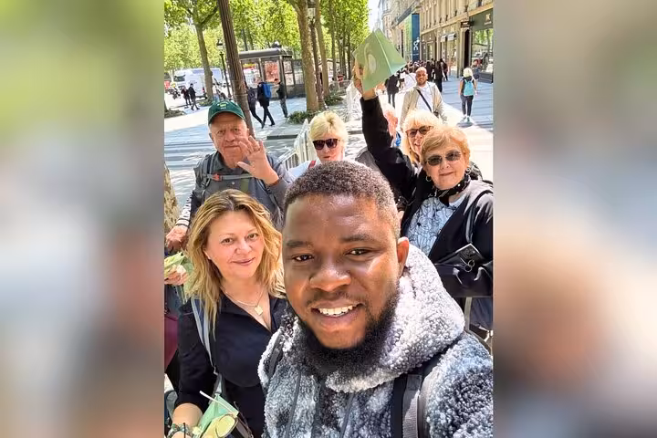 Private Paris walking tour group selfie on Champs-Élysées near Arc de Triomphe, tasting macarons