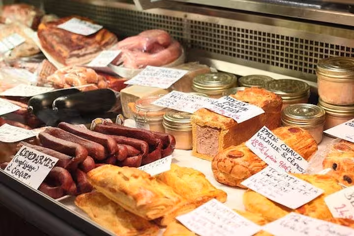 Display of gourmet meats and pastries at a Paris market, highlighting culinary delights on the Bastille food tour.