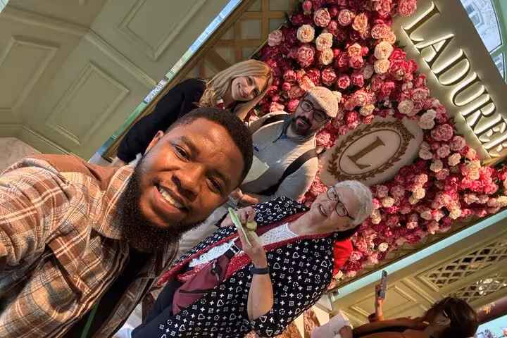 Guests pose at Ladurée flower wall during private Paris Champs-Élysées tour with macarons tasting