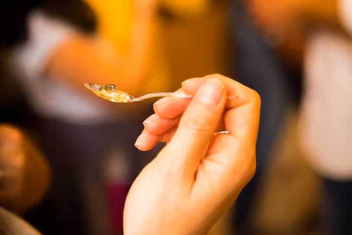 A close-up of a hand holding a spoonful of gourmet honey, tasting experience on a Paris food tour.