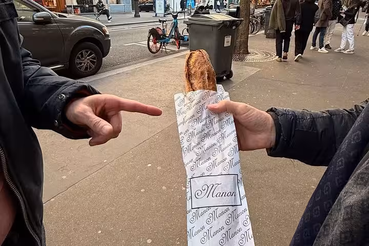 Sharing a warm pastry on Paris food, wine and cheese tasting tour with quirky Napoleon love story walk