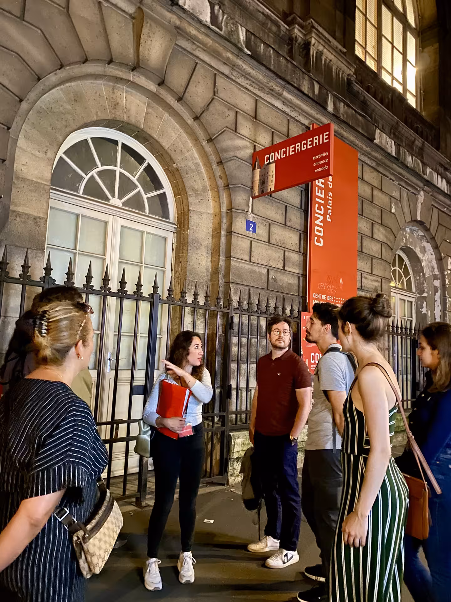 Tour guide explains the history of the Conciergerie to a group, highlighting its significance during the French Revolution.
