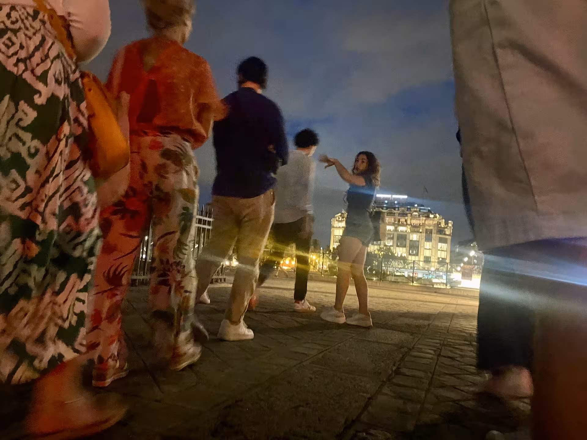 Tour guide leading a group on the Paris Justice and Crime Tour with illuminated buildings in the background.
