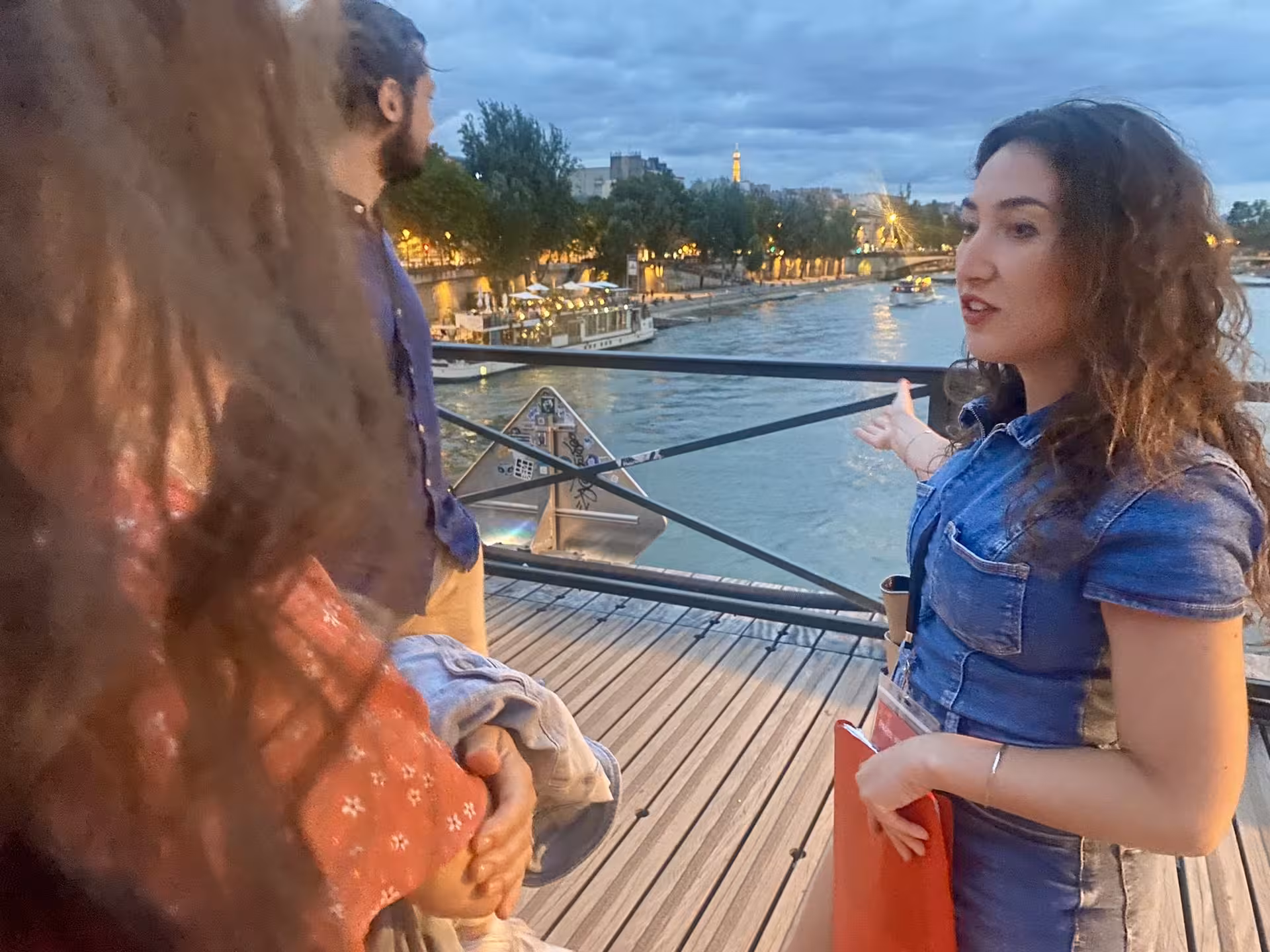 Guide explaining landmarks on the Paris Justice and Crime Tour by the Seine River during twilight.