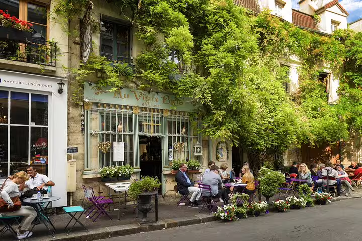 Charming Parisian café with lush greenery in Le Marais, showcasing outdoor dining for a walking food tour experience.