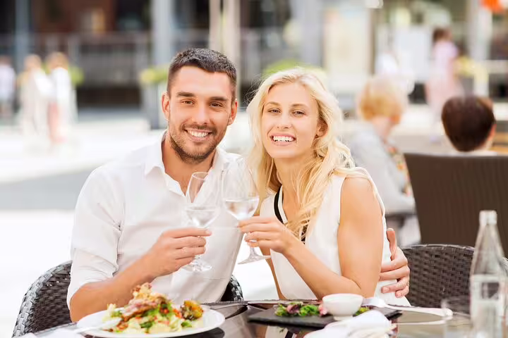 Couple enjoying a Paris Le Marais walking food tour with wine and French cuisine at an outdoor café, capturing local flavors.