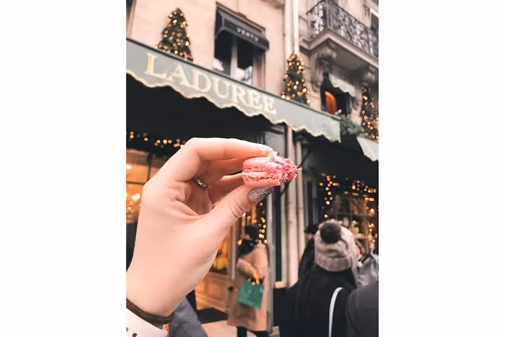 Hand holding pink macaron outside Ladurée on Champs-Élysées, Paris macaron tasting on private tour