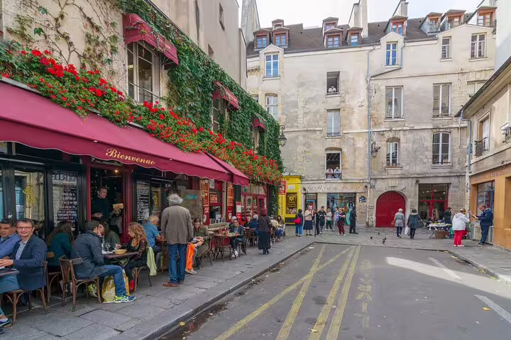 Charming Parisian street scene with people dining at a café, perfect for a crêpes and Eiffel Tower private tour experience.