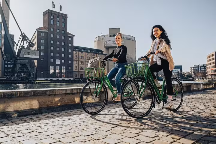 Friends on a Paris Seine bicycle tour, cycling by riverside landmarks with optional Louvre entrance upgrade