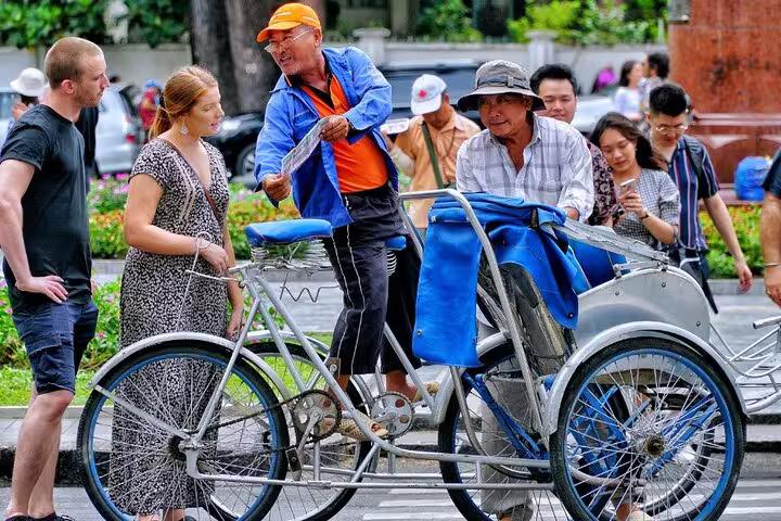 Guided Paris Seine bike tour group meeting a pedicab driver on a street, with optional Louvre entry add-on