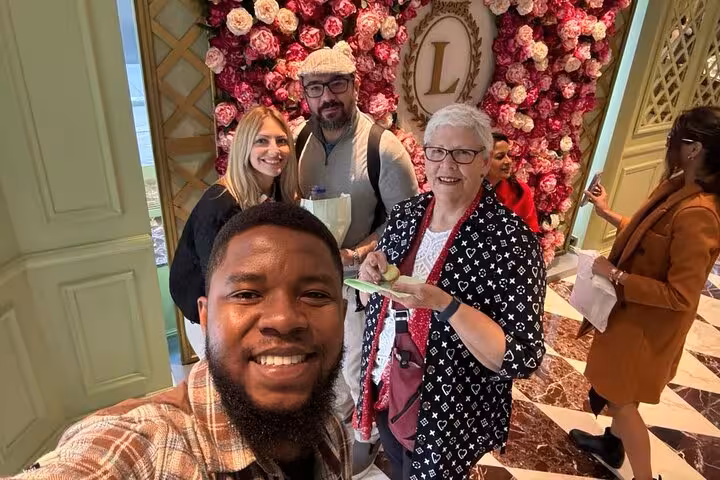 Small group photo at Ladurée floral backdrop on Champs-Élysées, private Paris tour and macaron stop