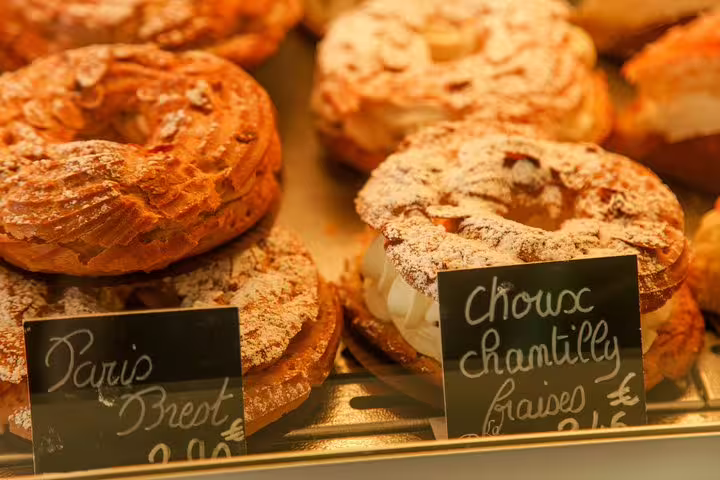 Close-up of delicious Parisian pastries, including Paris-Brest and choux chantilly, perfect for a family-friendly culinary tour.
