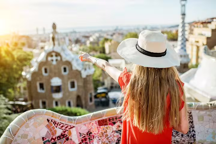 A tourist in a sunhat enjoys the vibrant architecture of Park Güell, Barcelona, during a private tour with tapas.