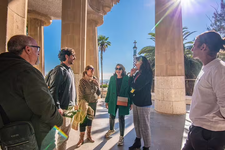 Visitors engage with a guide under Park Güell's iconic columns during a small group tour in Barcelona.