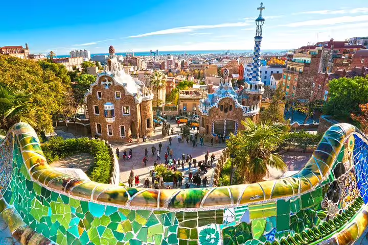 Vibrant view of Park Güell's iconic mosaic terrace overlooking Barcelona's skyline, featured in Barcelona Highlights Tour.
