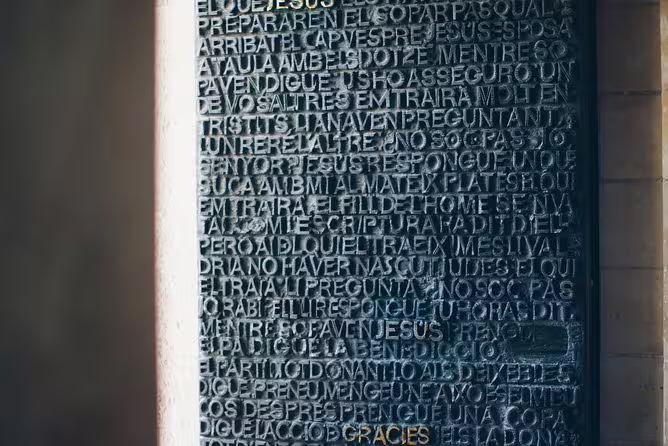 Close-up of intricately carved text on a door at the Sagrada Familia, showcasing detailed craftsmanship.
