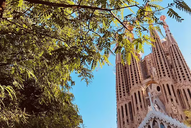Lush greenery framing the iconic towers of Park Guell under a clear blue sky, capturing Gaudí's architectural marvel.