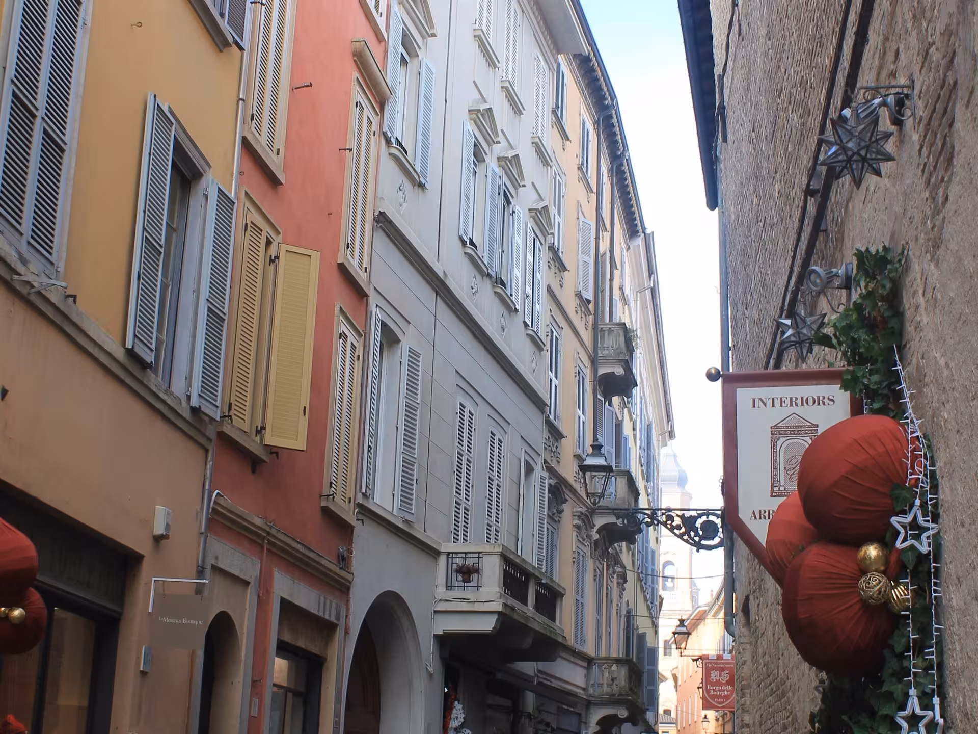 Charming street view in Parma with colorful buildings and festive decorations, perfect for sightseeing on a food tour.