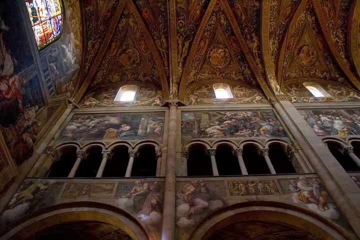 Frescoed vaulted ceiling and ornate arches inside a historic church visited on a private Parma walking tour in Italy