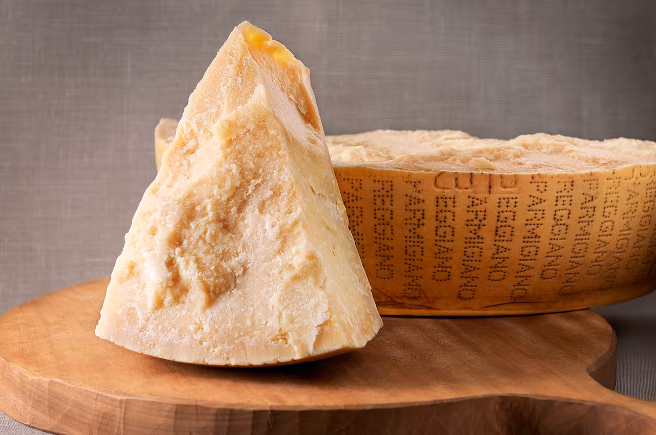 Close-up of Parmigiano Reggiano cheese wedge on a wooden board, highlighting its rich texture for gourmet tours.
