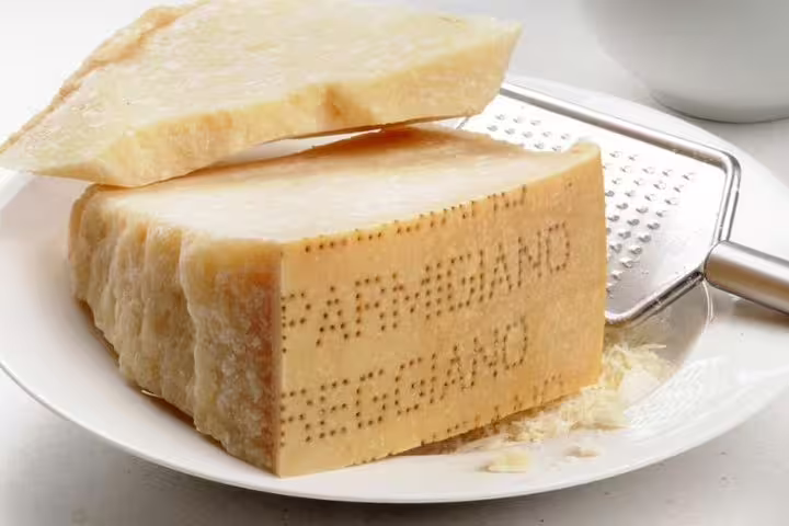 Close-up of authentic Parmigiano-Reggiano cheese wedge ready for grating in Parma tour.