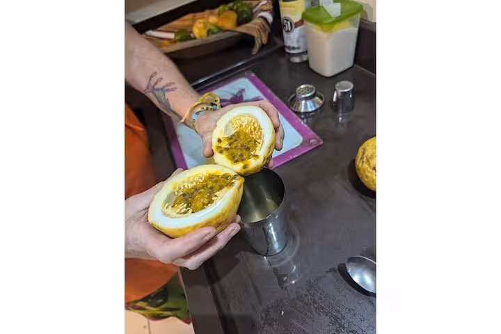 A person holding a halved passion fruit ready for use in a Bahian recipe at a cooking class.