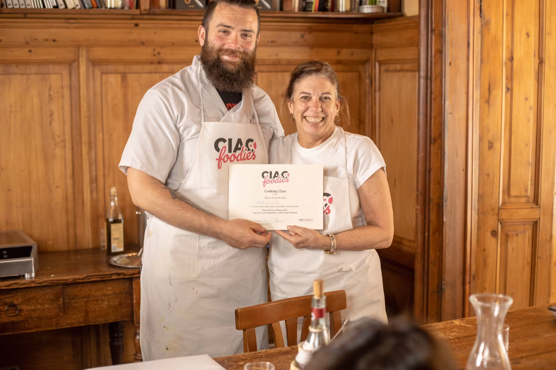 Two smiling participants holding a cooking class certificate at Pasta Lovers Cooking Class in Florence.