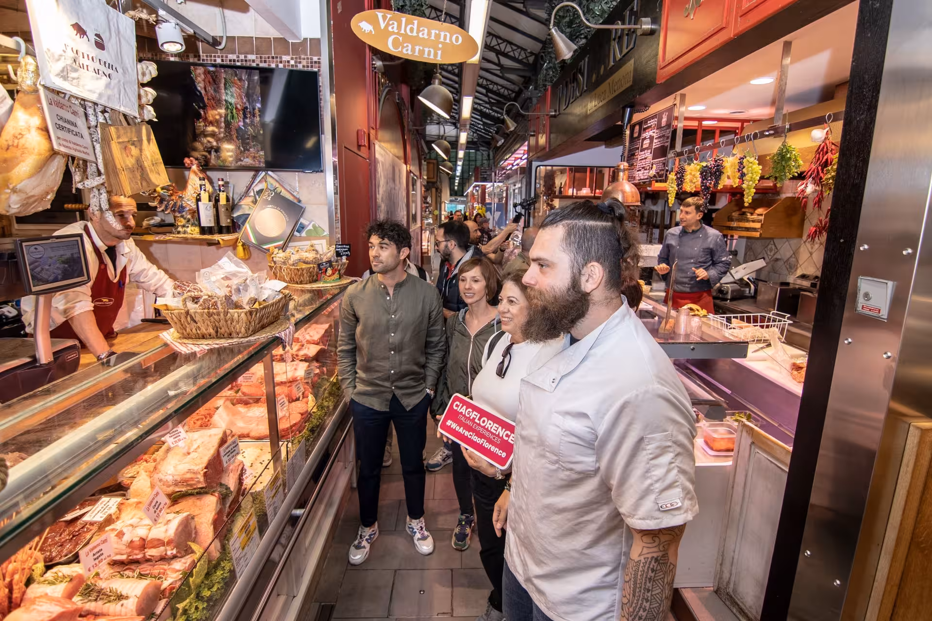 Participants explore a bustling butcher shop in Sant’Ambrogio Market during the Pasta Lovers Cooking Class tour in Florence.