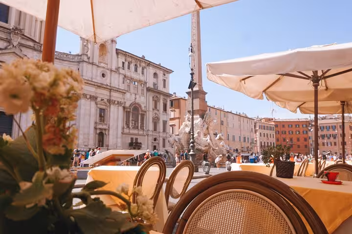 Charming outdoor café setting in Piazza Navona, Rome, ideal for enjoying a pasta cooking class experience.
