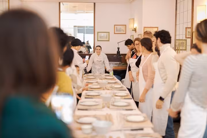 Participants in a pasta cooking class in Rome gather around a table, ready to learn and create fettuccine.